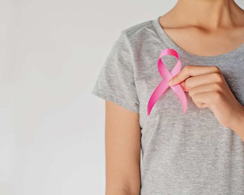 Rosa Brustkrebs-Bewusstseinsband auf grauem T-Shirt, symbolisiert Solidarität im Kampf gegen Brustkrebs.